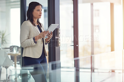 Buy stock photo Shot of a young businesswomen using a digital tablet in an office