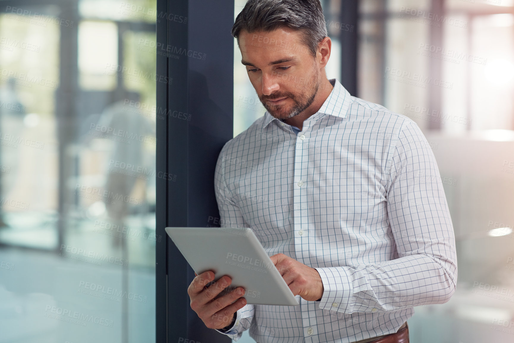 Buy stock photo Shot of a businessman using a digital tablet in an office