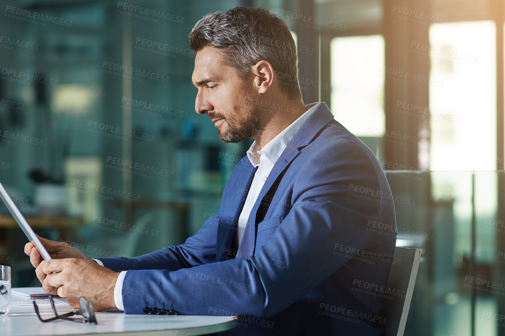 Buy stock photo Shot of a businessman using a digital tablet while woking late at the office