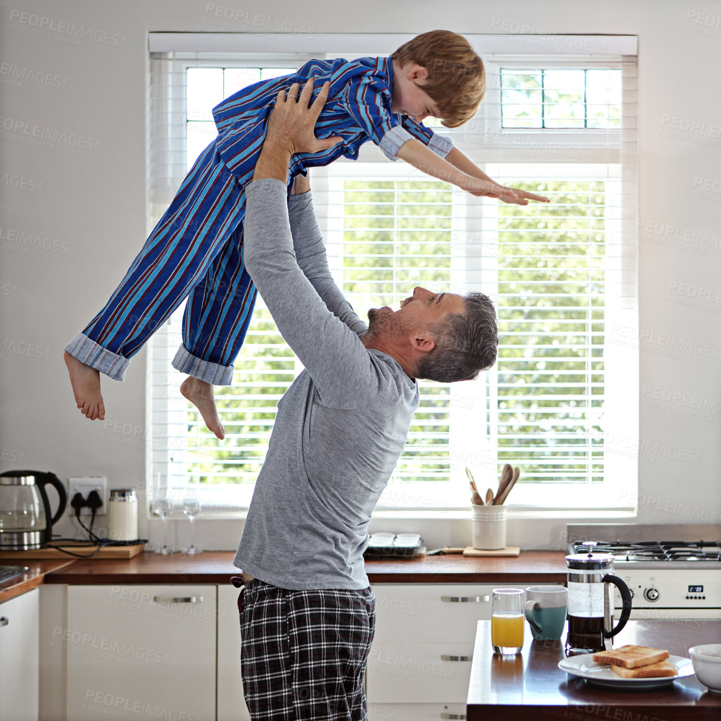 Buy stock photo Kitchen, father and flying with boy for bonding, fun or happy in morning with pajama. Apartment, people and parent for lifting with smile for support, care and playful for child development at home