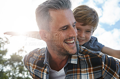 Buy stock photo Shot of a father and son enjoying a piggyback ride outdoors