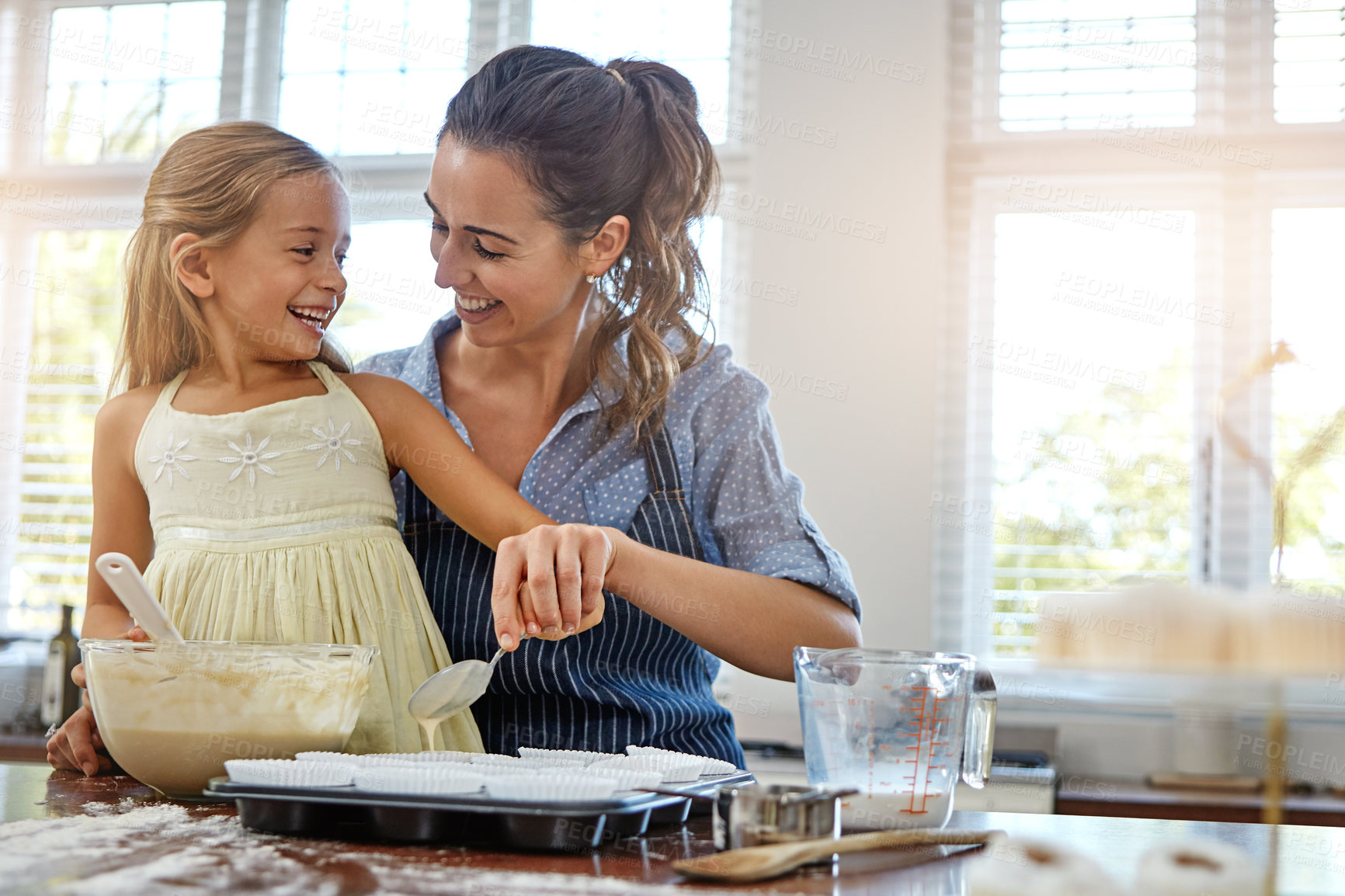 Buy stock photo Mother, girl and baking support in kitchen with helping, culinary education and teaching muffin recipe. Family, woman and kid with batter preparation for cooking, bonding or child development in home