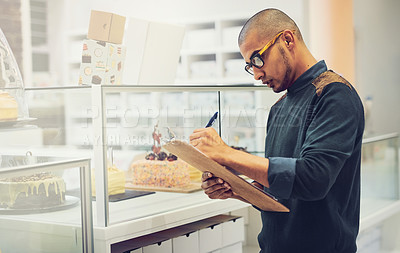 Buy stock photo Shot of a coffee shop owner writing on his clipboard