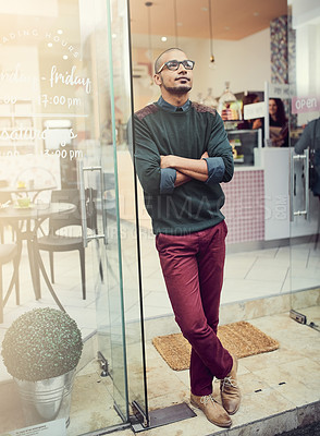 Buy stock photo Shot of a young man standing in the entrance of a cafe