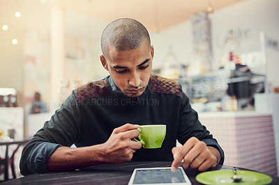 Buy stock photo Shot of a young man sitting in a cafe with his digital tablet