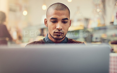 Buy stock photo Shot of a young man using his laptop in a cafe