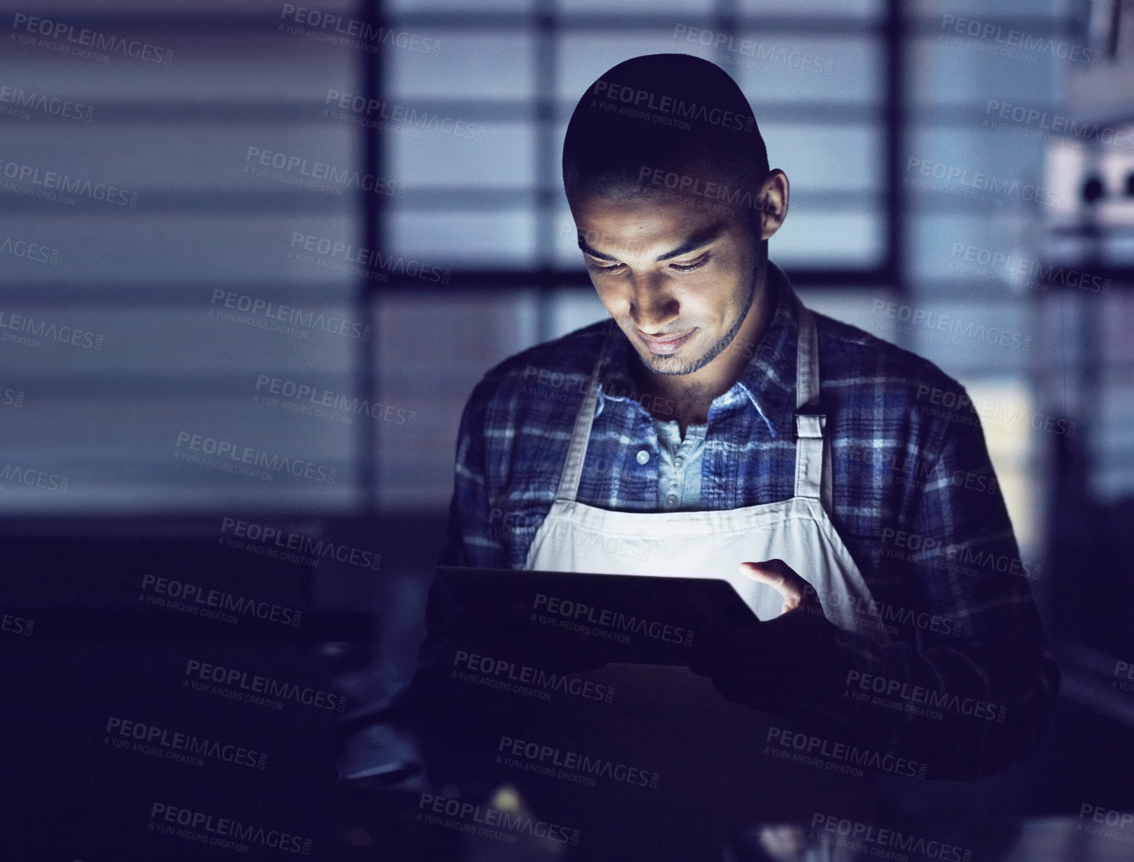 Buy stock photo Shot of a young man working late on a digital tablet in his coffee shop