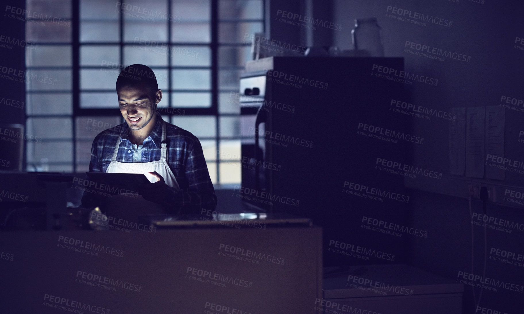 Buy stock photo Shot of a young man working late on a digital tablet in his coffee shop