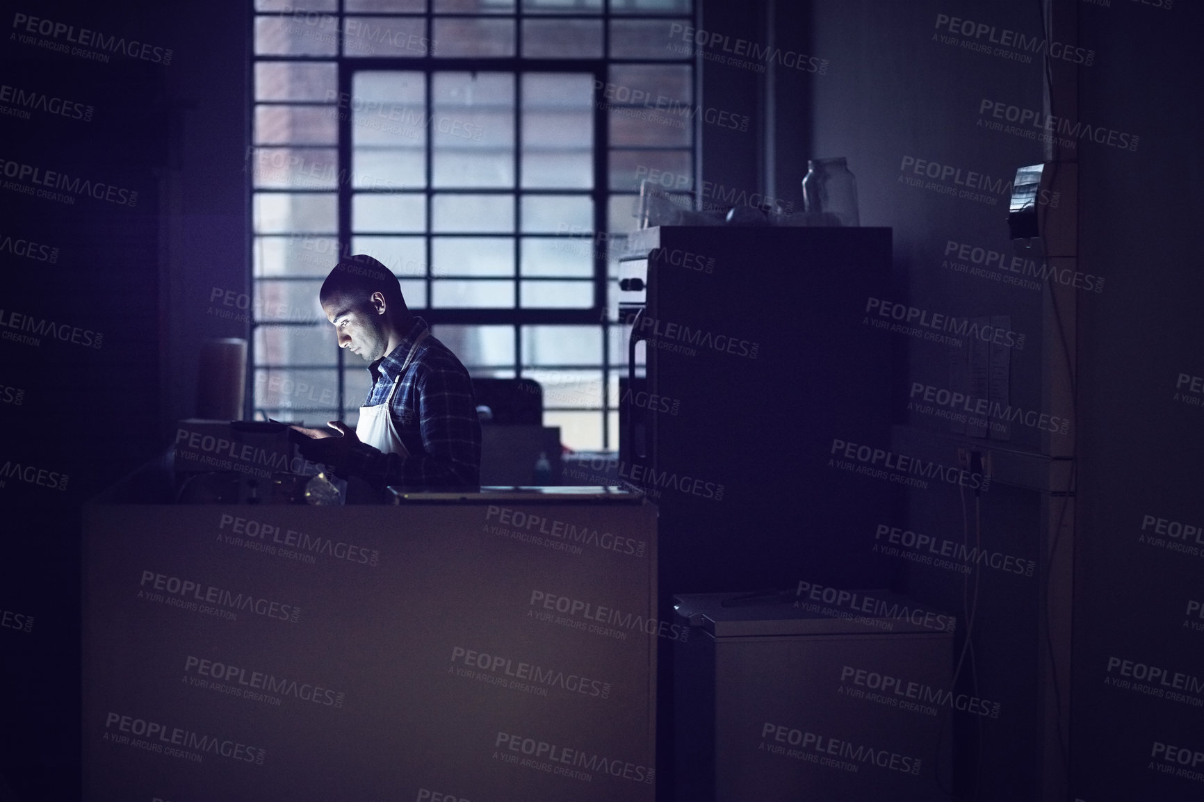 Buy stock photo Shot of a young man working late on a digital tablet in his coffee shop