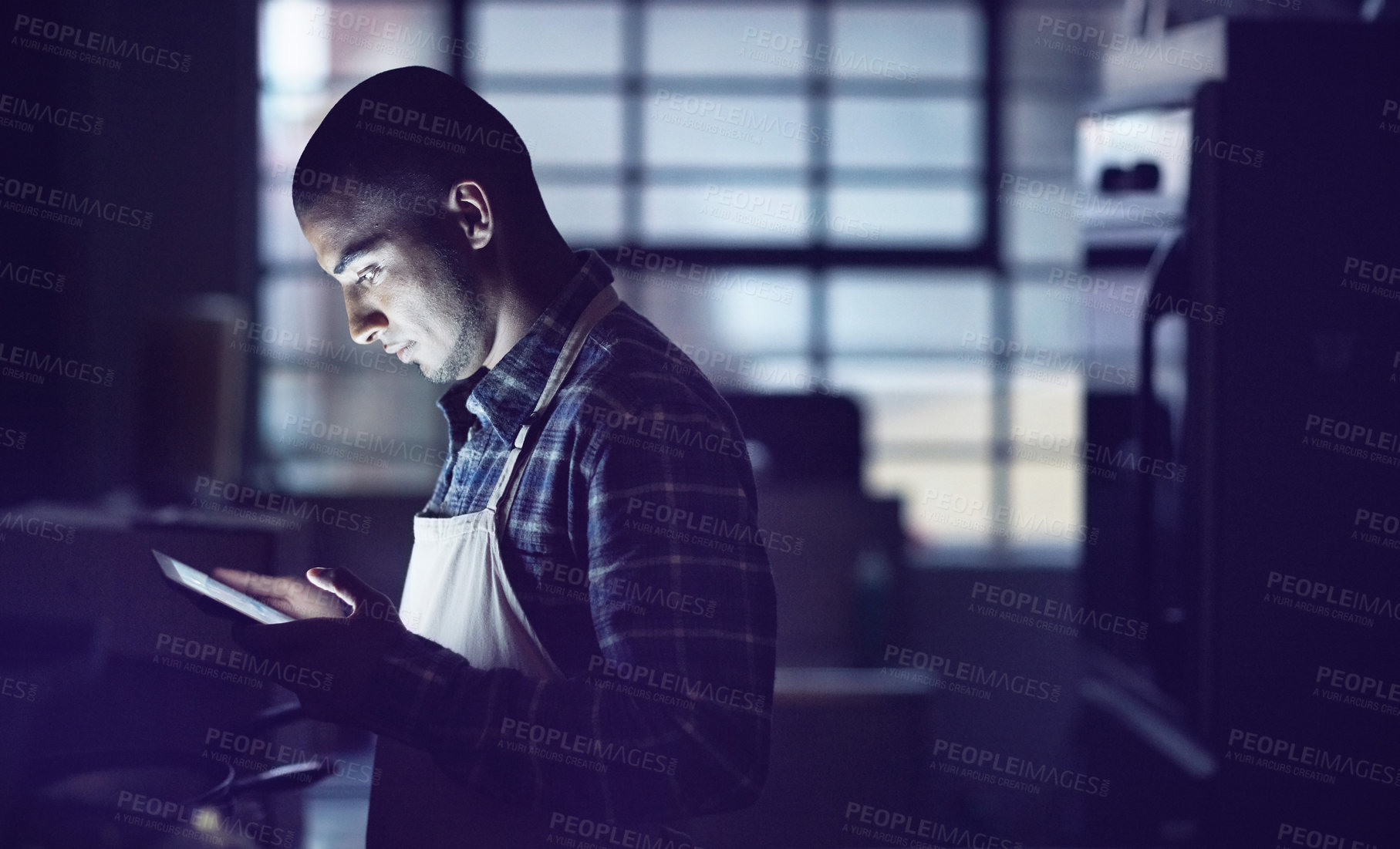 Buy stock photo Shot of a young man working late on a digital tablet in his coffee shop