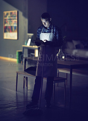 Buy stock photo Shot of a young man working late on a digital tablet in his coffee shop