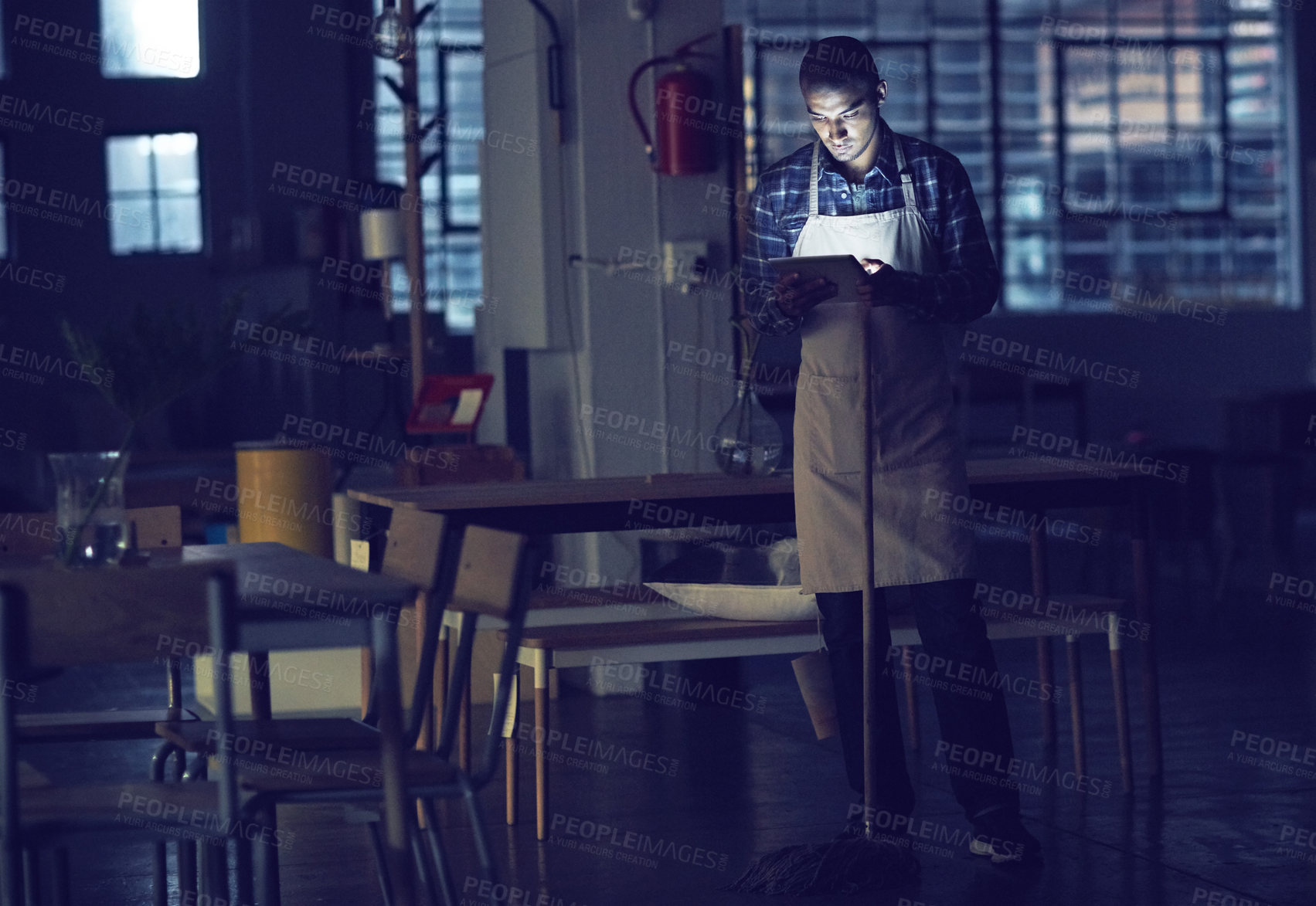 Buy stock photo Shot of a young man working late on a digital tablet in his coffee shop