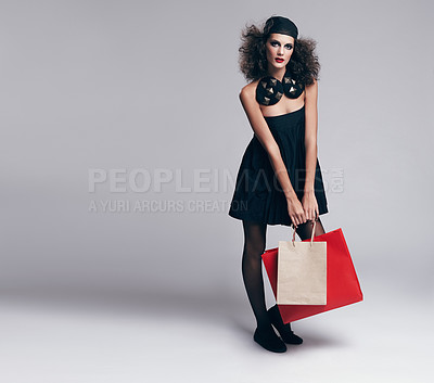 Buy stock photo Studio portrait of a beautiful young fashion model carrying shopping bags against a gray background