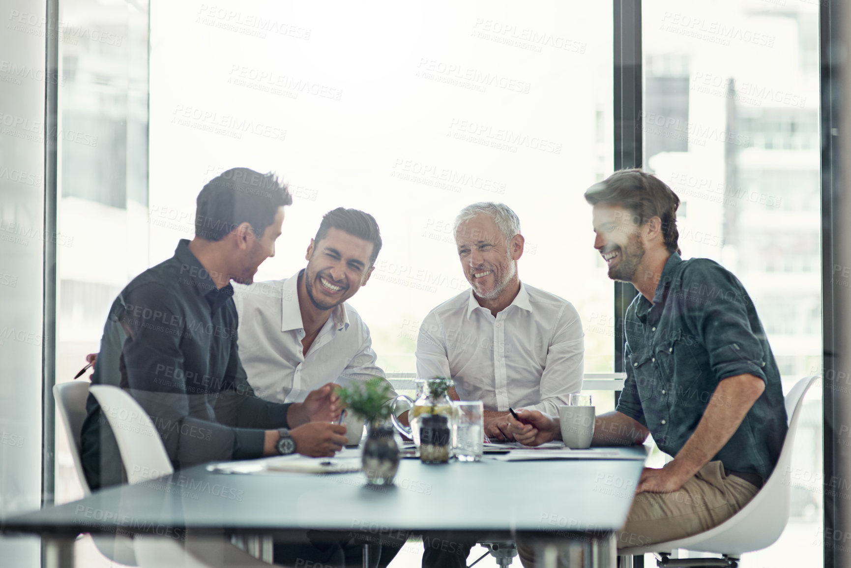 Buy stock photo Shot of a group of businessmen having a meeting around a table in an office