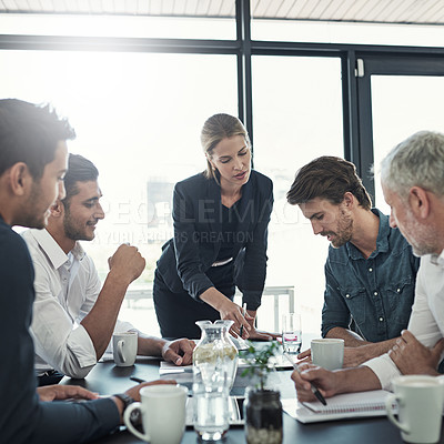 Buy stock photo Shot of a businesswoman talking to colleagues sitting around a table in an boardroom