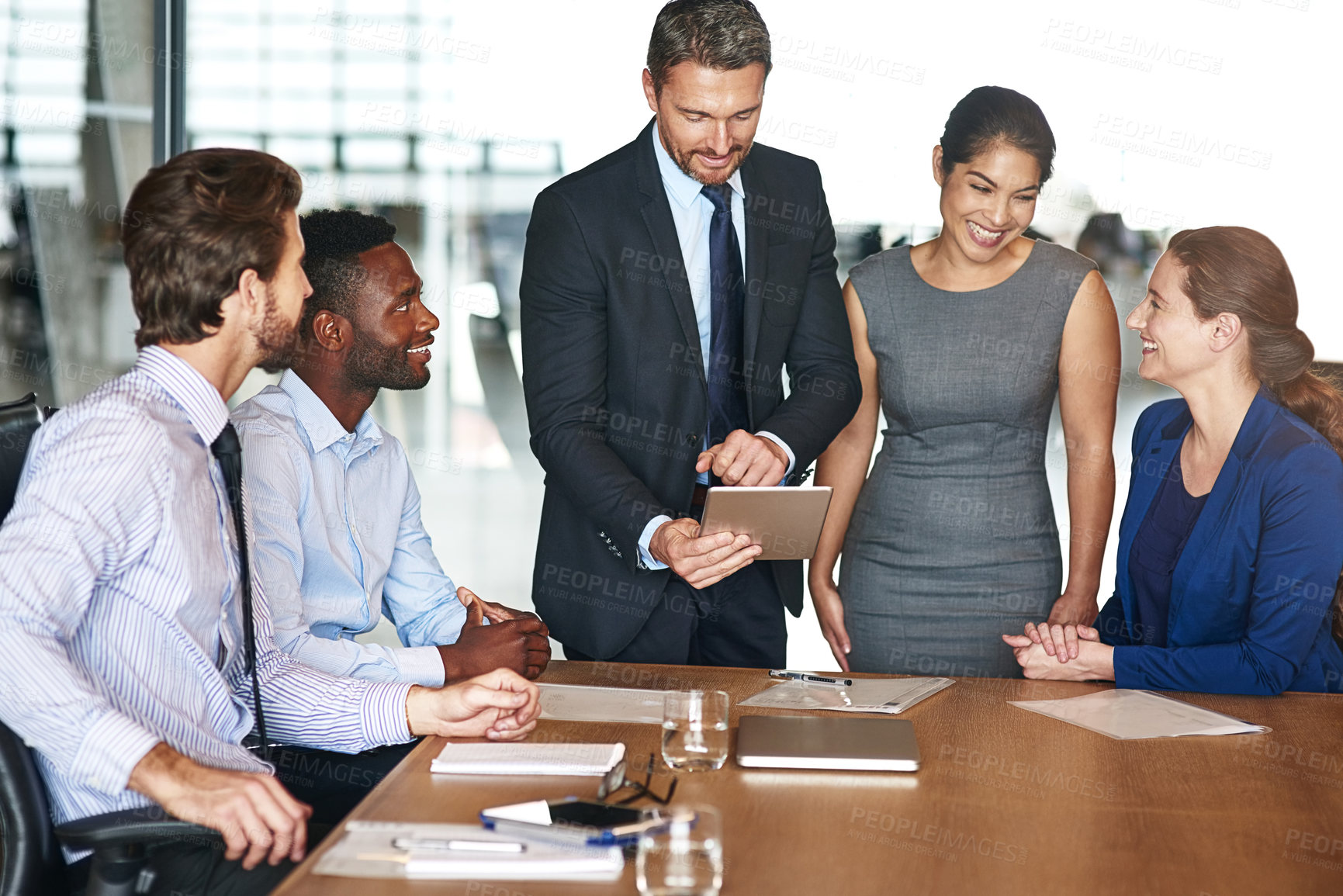 Buy stock photo Shot of a group of corporate colleagues talking together over a digital tablet in an office