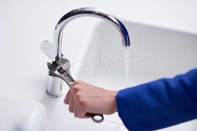 Buy stock photo Cropped shot of a plumber repairing a tap with a wrench
