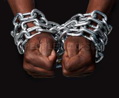 Buy stock photo Cropped shot of a man’s hands tied up with chains against a black background