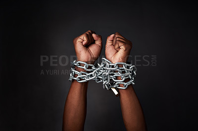 Buy stock photo Cropped shot of a man’s hands tied up with chains against a black background