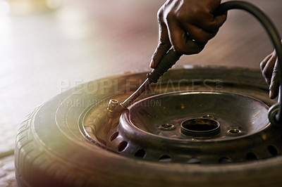 Buy stock photo Cropped shot of a mechanic pumping up a car tyre