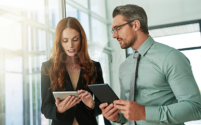 Buy stock photo Cropped shot of two businesspeople using their tablets in the office