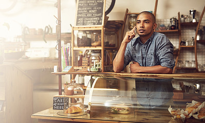 Buy stock photo Shot of a young entrepreneur using a phone in his store