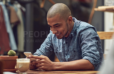 Buy stock photo Shot of a young man using his phone in a cafe
