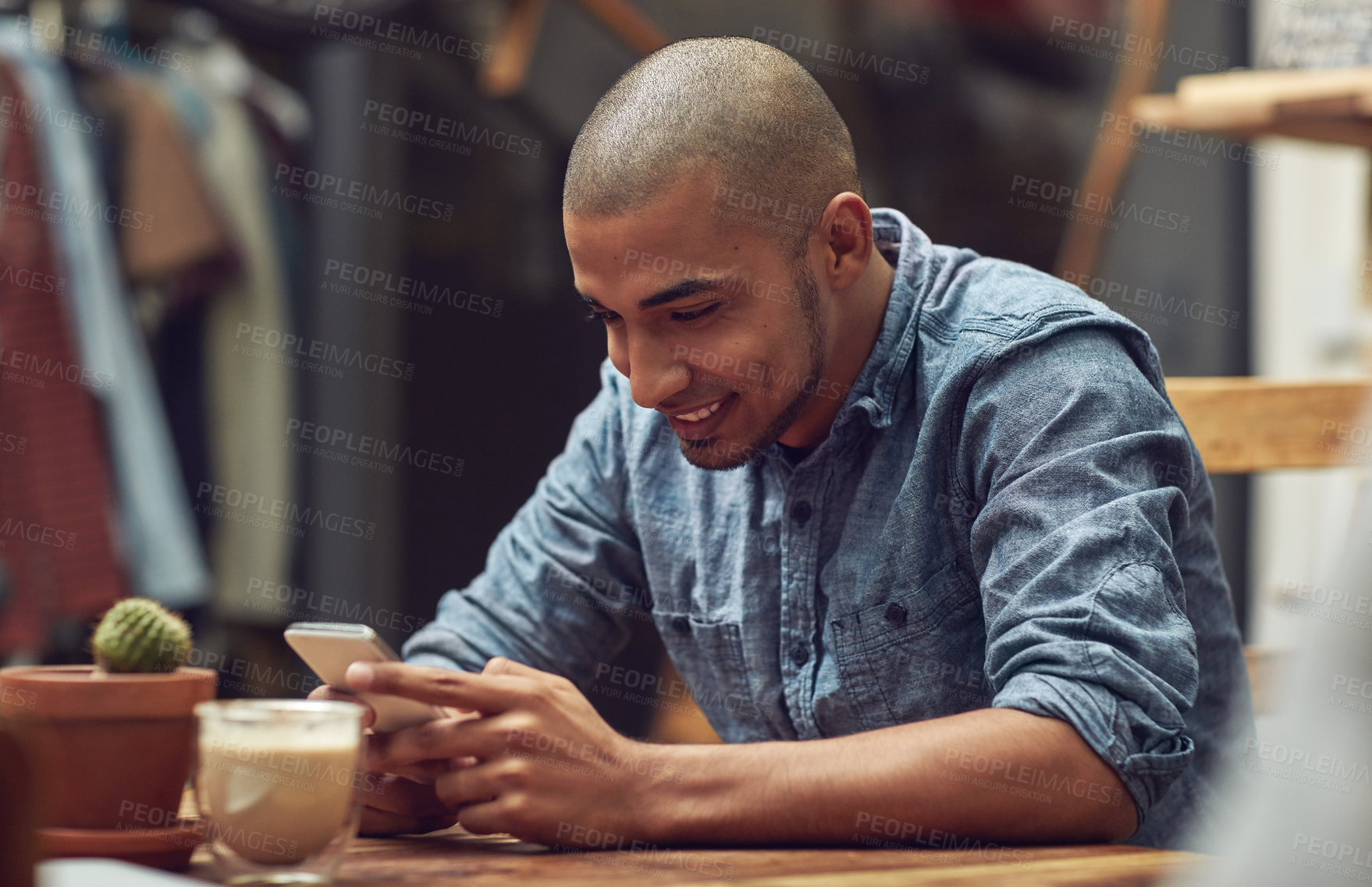 Buy stock photo Shot of a young man using his phone in a cafe