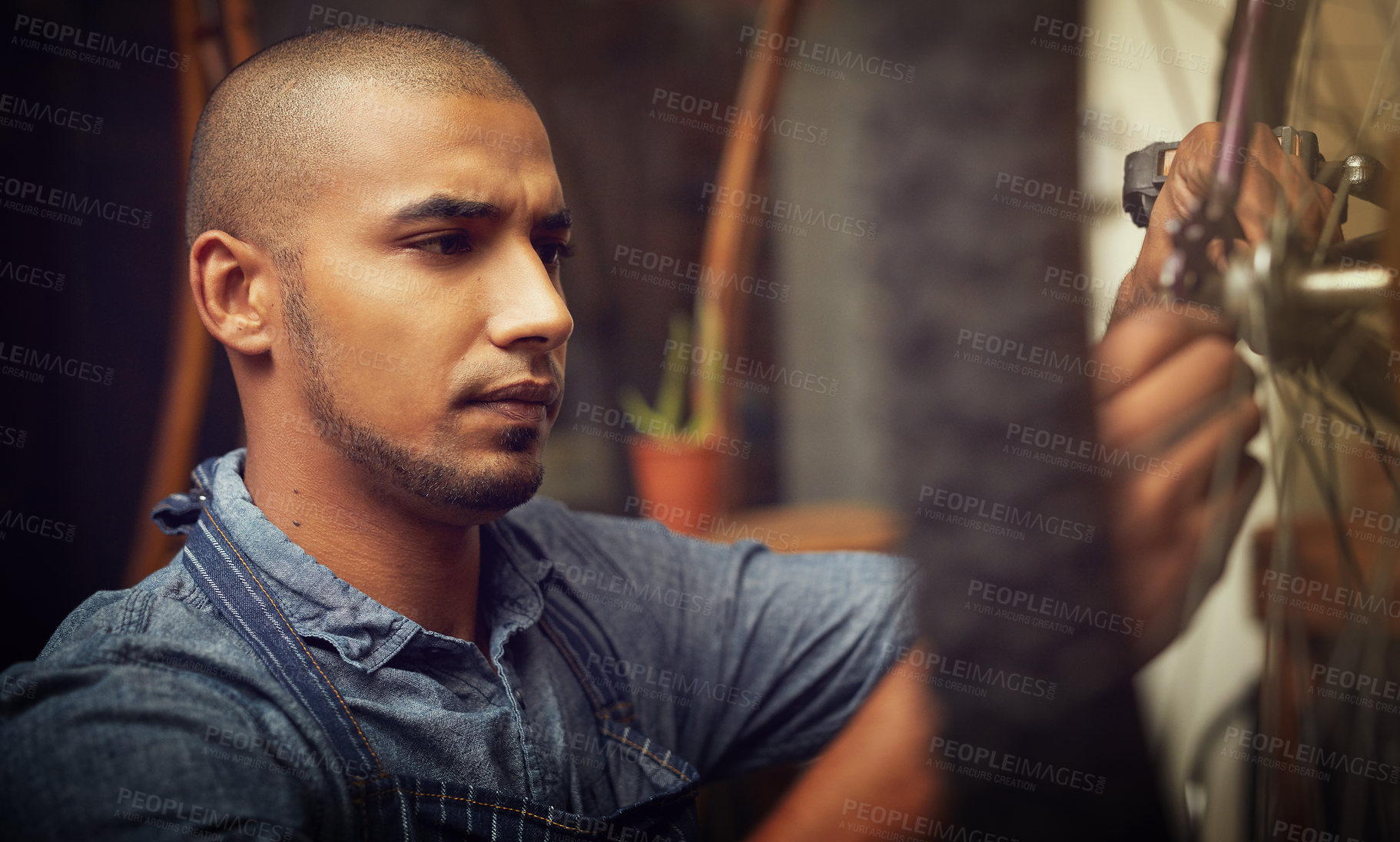 Buy stock photo Employee, man and mechanic on bicycle wheel for fixing, repairs or maintenance at workshop. Male person, small business and serious handyman at garage for service, inspection and safety as technician