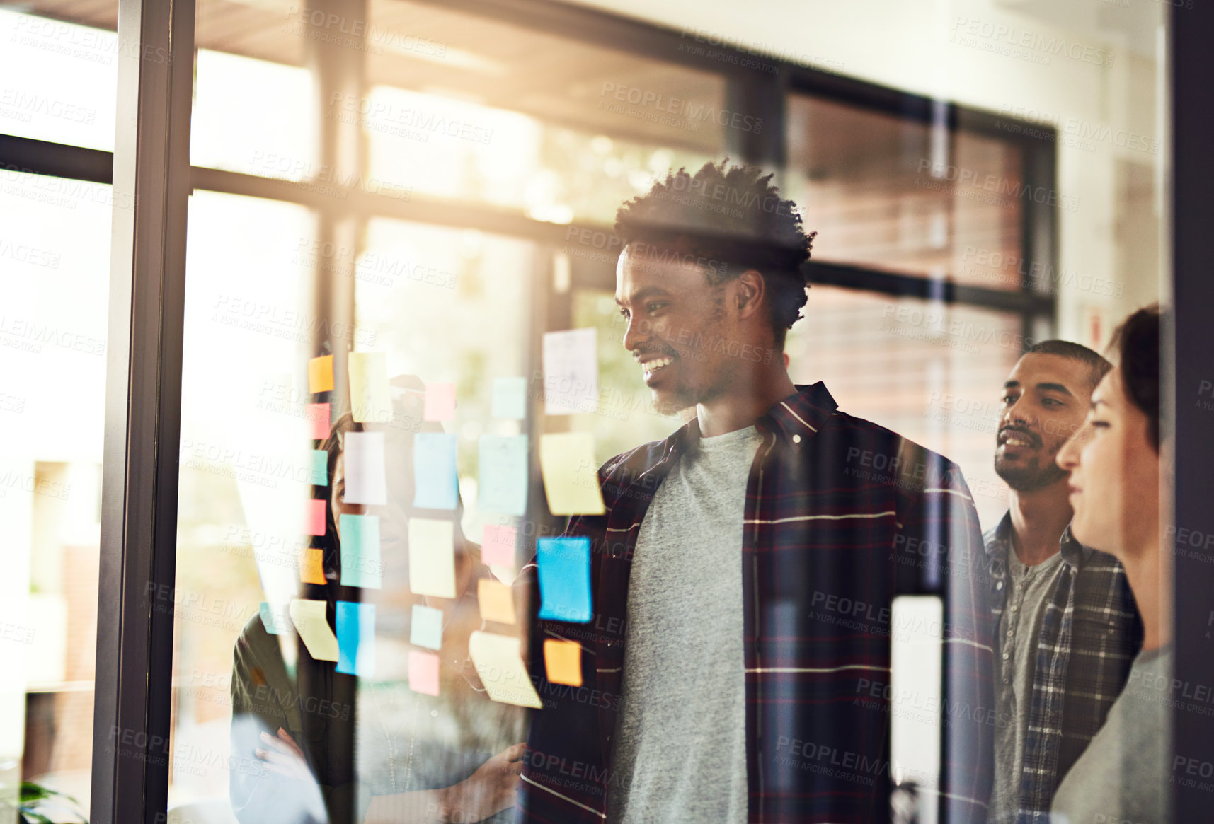 Buy stock photo Cropped shot of coworkers using sticky notes on a glass wall during an office meeting