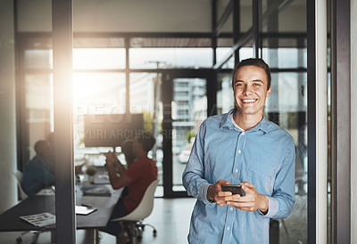 Buy stock photo Portrait of a young businessman standing in an office with colleagues in the background