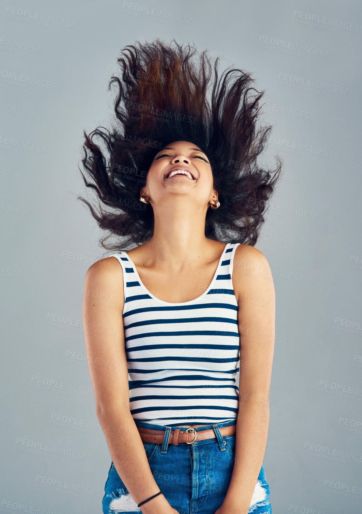 Buy stock photo Happy woman, carefree and hair with flip in casual clothing, fashion or studio on a gray background. Young, female person or model with smile in satisfaction for freedom, fun or cheerful attitude