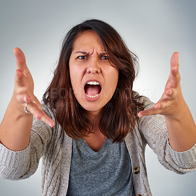 Buy stock photo Portrait of an angry young woman yelling against a grey background