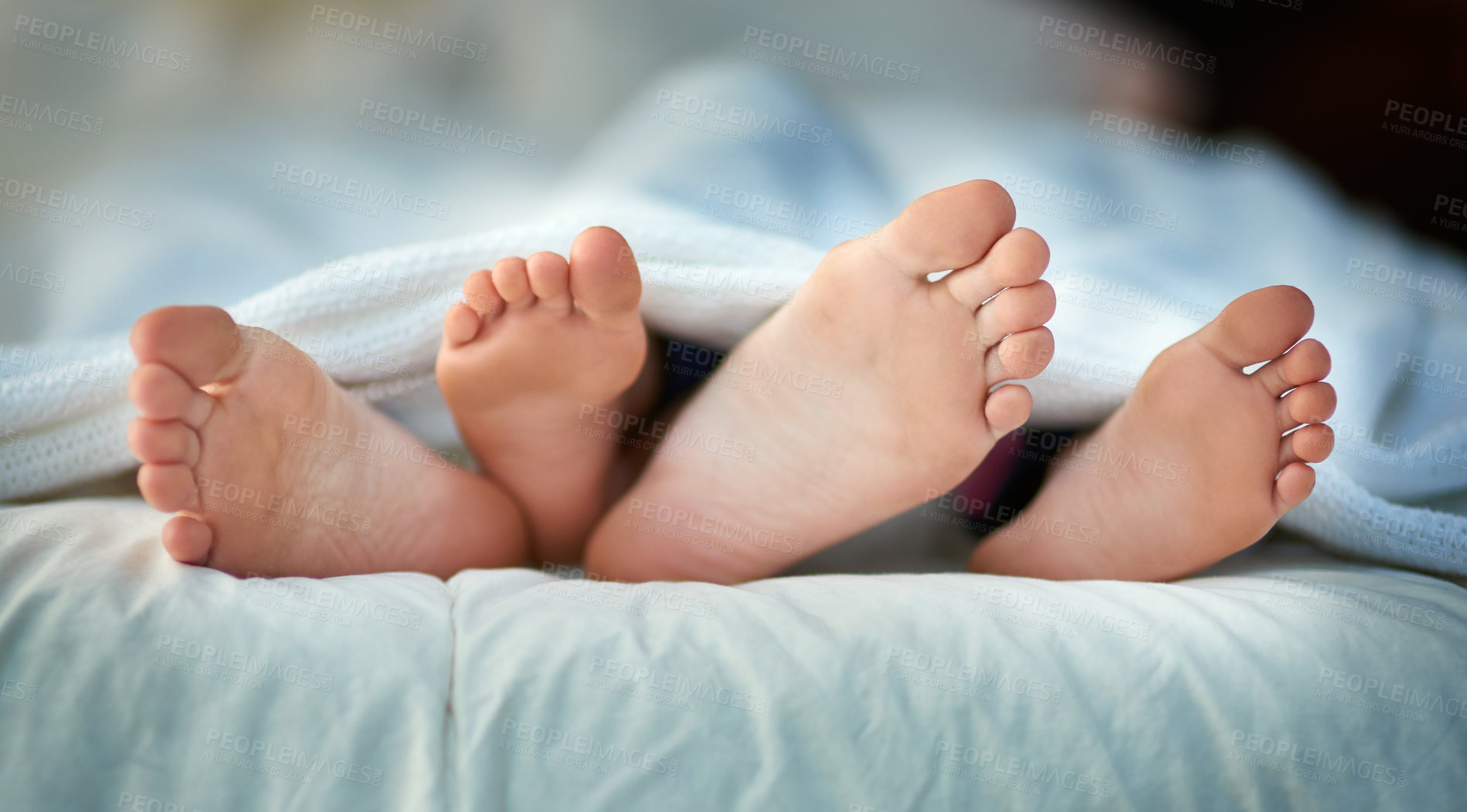 Buy stock photo Cropped shot of a parent and child's feet sticking out under covers