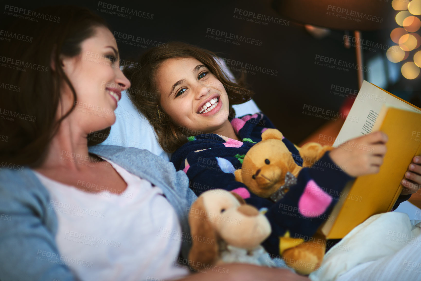 Buy stock photo Mother and daughter reading together in bed