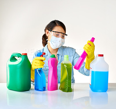 Buy stock photo Cropped shot of a young woman holding various bottles of detergents