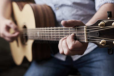 Buy stock photo Cropped shot of an unrecognizable man playing an acoustic guitar at home