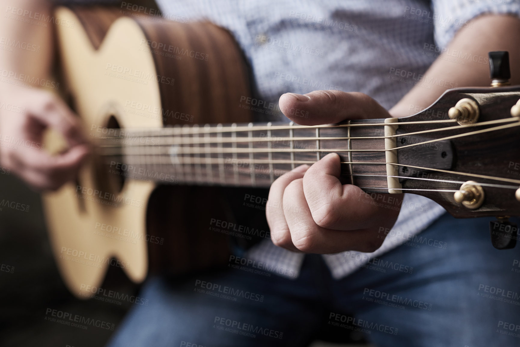 Buy stock photo Cropped shot of an unrecognizable man playing an acoustic guitar at home