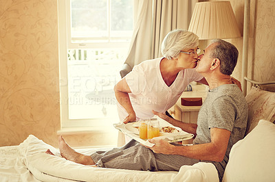 Buy stock photo Shot of a senior woman bringing breakfast in bed to her husband
