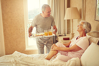 Buy stock photo Shot of a senior man bringing breakfast in bed to his wife