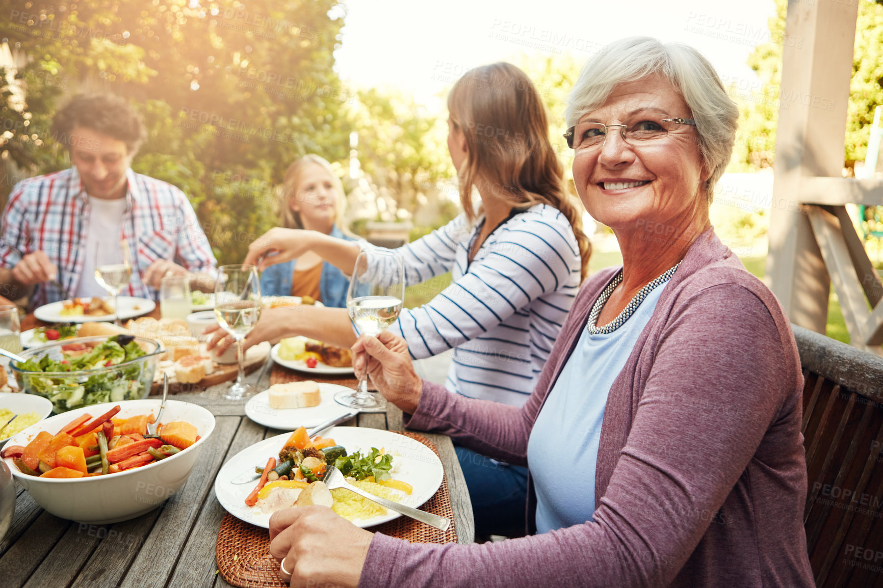 Buy stock photo Portrait of a happy elderly woman enjoying an outdoor lunch with her family