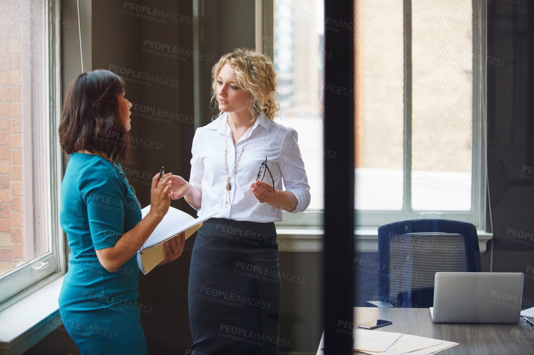 Buy stock photo Shot of two businesswomen having a discussion in an office