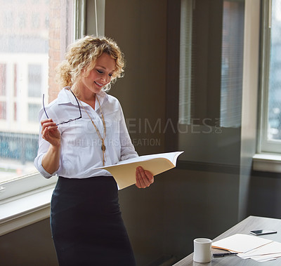 Buy stock photo Shot of a businesswoman reading a report in an office