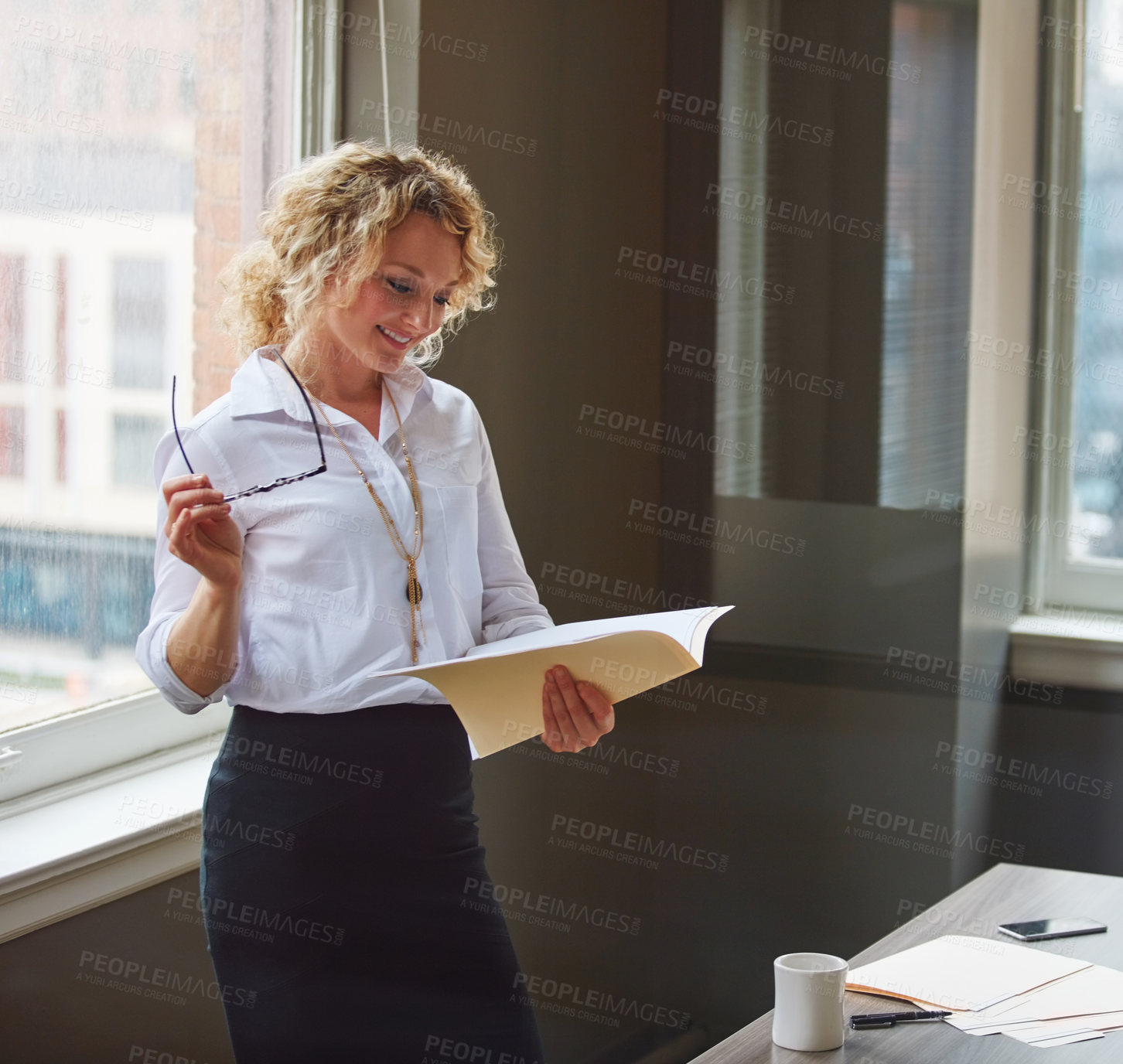 Buy stock photo Shot of a businesswoman reading a report in an office