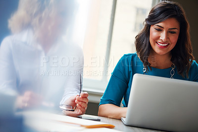 Buy stock photo Shot of two businesswomen using a laptop together in an office