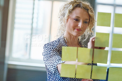 Buy stock photo Shot of a businesswoman brainstorming with adhesive notes on a glass wall in an office