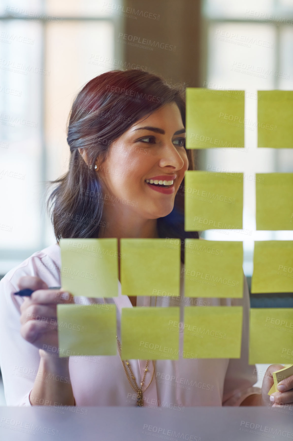 Buy stock photo Shot of a businesswoman brainstorming with adhesive notes on a glass wall in an office