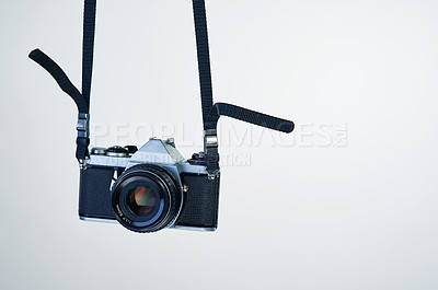 Buy stock photo Studio shot of a camera hanging by its strap