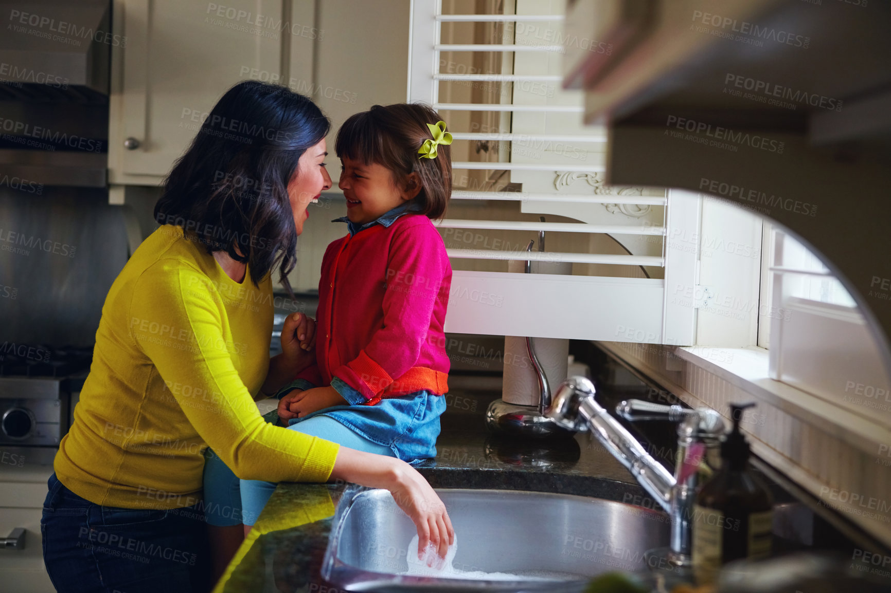 Buy stock photo Shot of a young mother and her daughter bonding by the kitchen sink