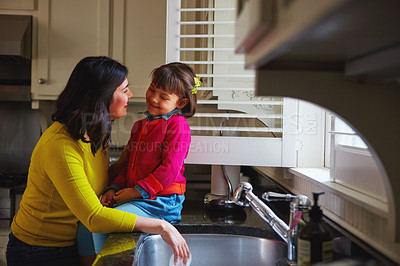 Buy stock photo Shot of a young mother and her daughter bonding by the kitchen sink